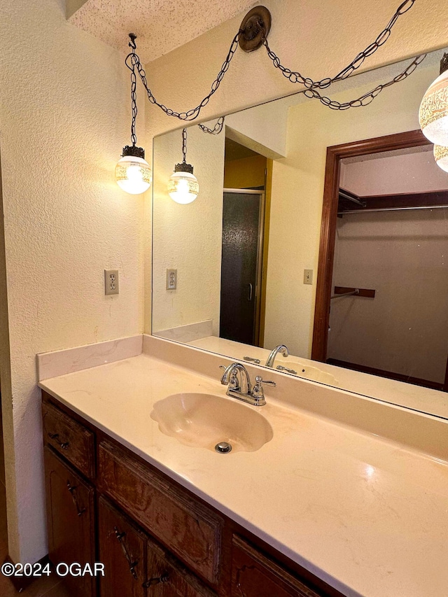 bathroom with vanity, a shower with door, and a textured ceiling