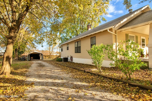 view of side of home with central AC unit and a carport