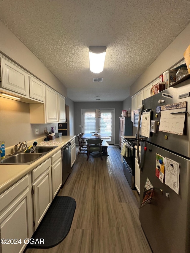 kitchen featuring dark wood-type flooring, a textured ceiling, sink, appliances with stainless steel finishes, and decorative light fixtures