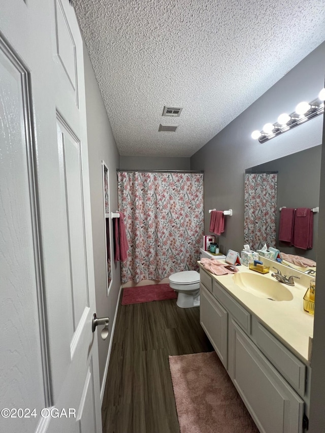 bathroom with wood-type flooring, toilet, a textured ceiling, vanity, and a shower with shower curtain