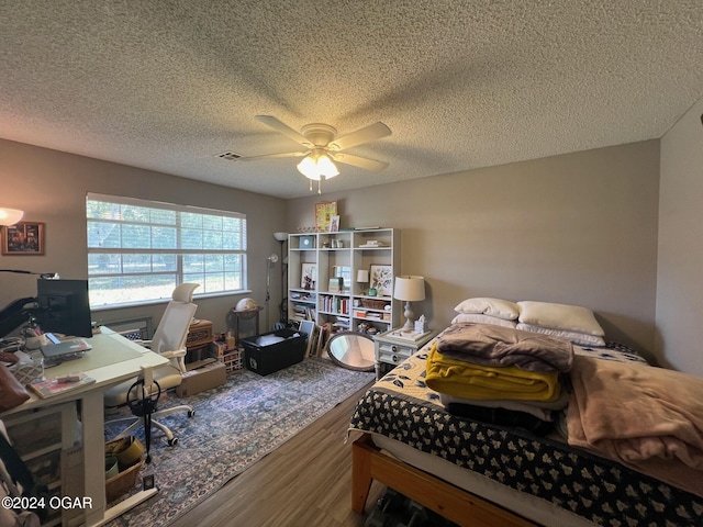 bedroom with a textured ceiling, hardwood / wood-style flooring, and ceiling fan