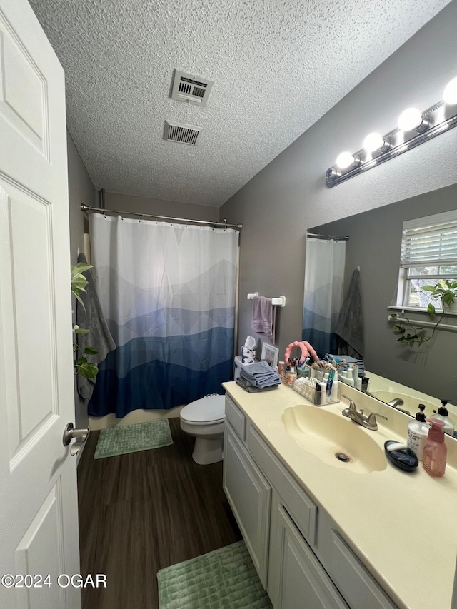 bathroom featuring wood-type flooring, a shower with curtain, vanity, a textured ceiling, and toilet