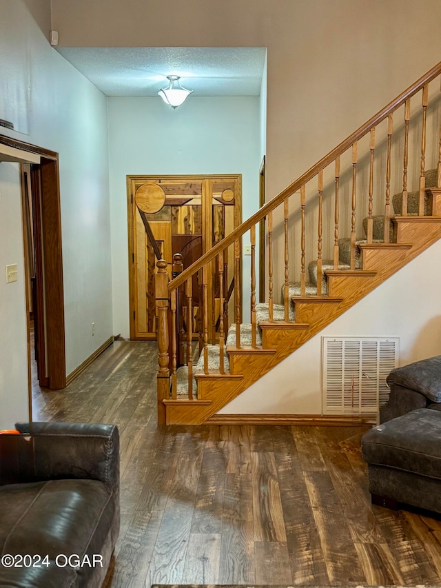 staircase with wood-type flooring and a textured ceiling