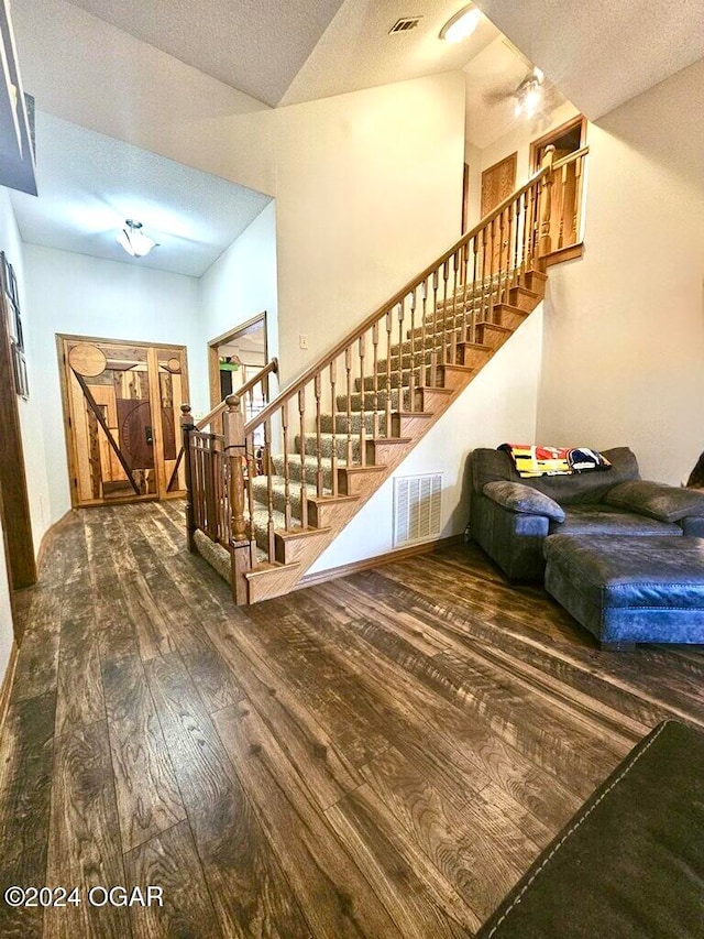 interior space featuring a textured ceiling, hardwood / wood-style flooring, and vaulted ceiling