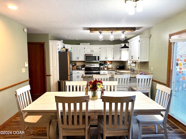 dining area with dark hardwood / wood-style flooring, sink, and a textured ceiling