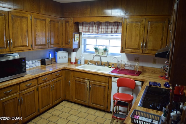 kitchen featuring tasteful backsplash, sink, stovetop, and range hood