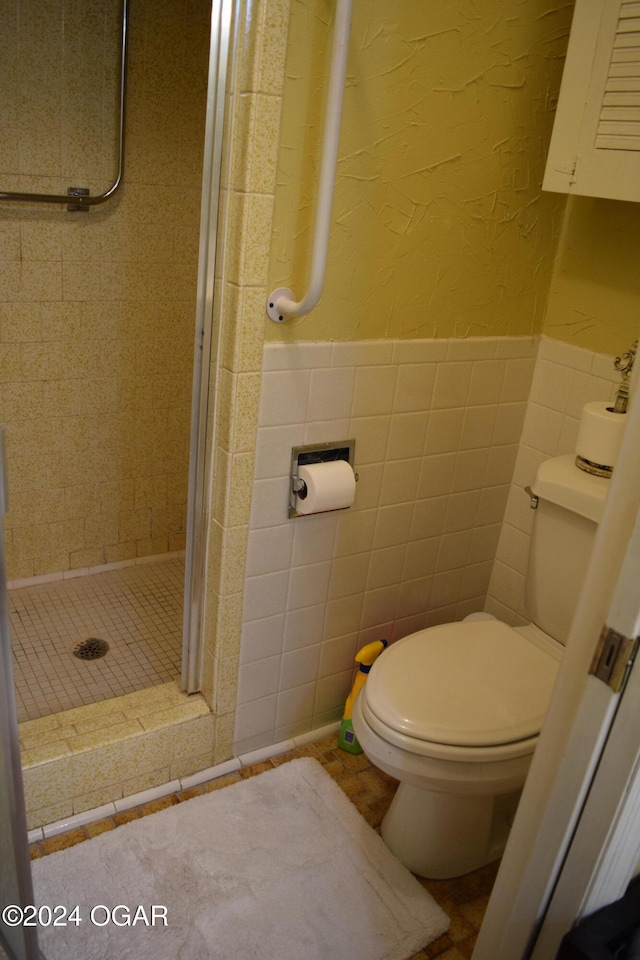 bathroom featuring tile patterned floors, toilet, tiled shower, and tile walls