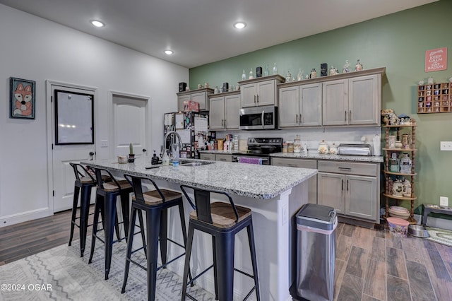 kitchen featuring light stone countertops, sink, black electric range, dark hardwood / wood-style floors, and an island with sink