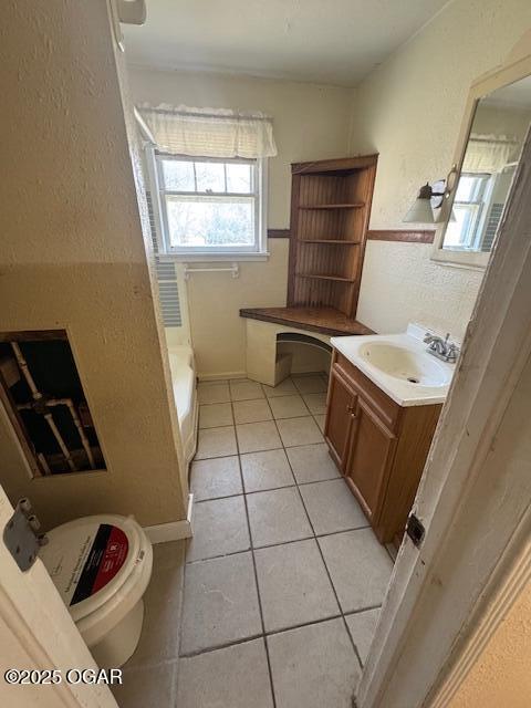 bathroom with toilet, vanity, a bath, and tile patterned flooring