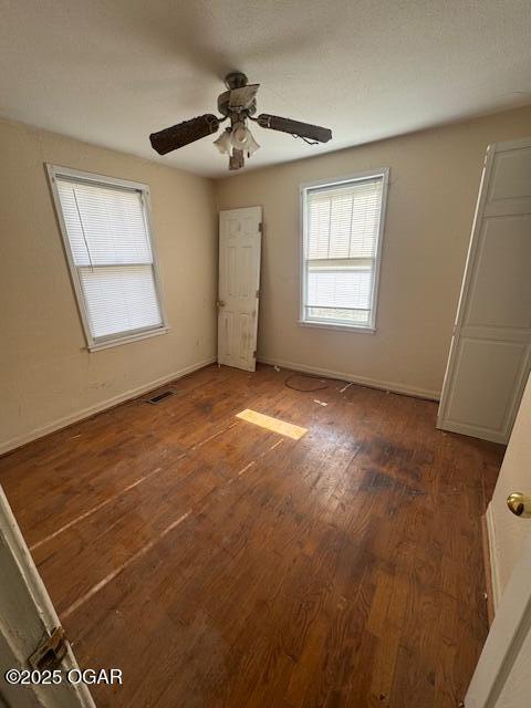 unfurnished bedroom featuring dark wood-type flooring and ceiling fan