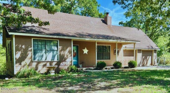 view of front of home with a front yard, a porch, and a garage