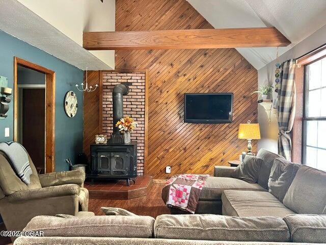 living room featuring beam ceiling, a wood stove, wooden walls, and high vaulted ceiling