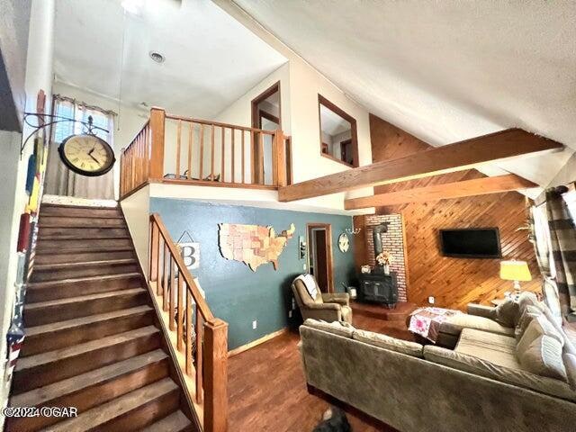 living room featuring wooden walls and high vaulted ceiling