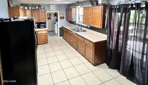 kitchen with light tile patterned floors, sink, and black appliances