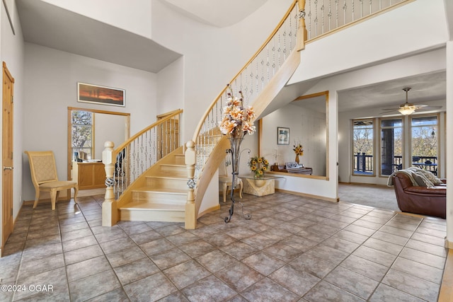 stairway with a high ceiling, tile patterned floors, and ceiling fan