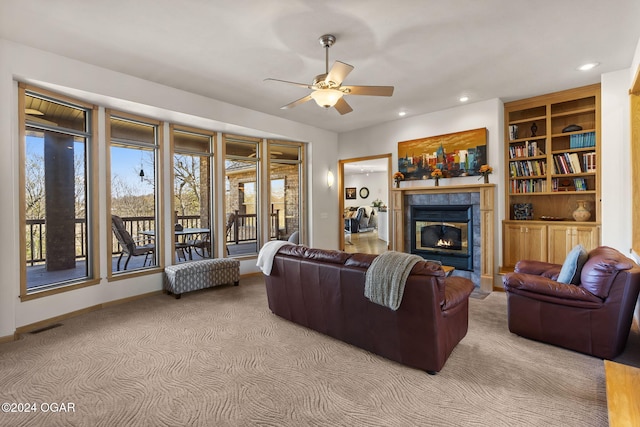 living room featuring a tile fireplace, light colored carpet, and ceiling fan