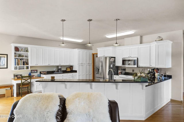 kitchen with light wood-type flooring, stainless steel appliances, white cabinetry, and hanging light fixtures