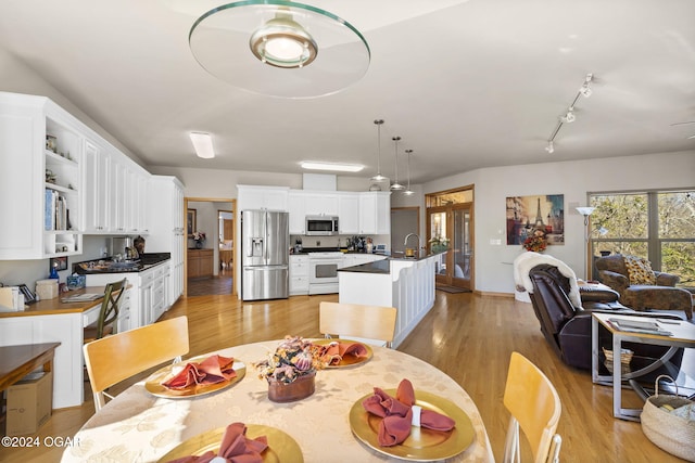 dining area featuring light wood-type flooring, track lighting, ceiling fan, and sink