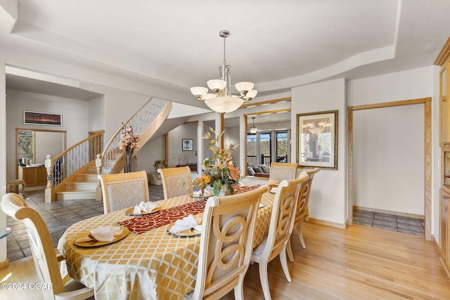 dining area featuring a tray ceiling, light hardwood / wood-style flooring, and a notable chandelier