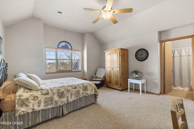 bedroom with light carpet, ensuite bathroom, vaulted ceiling, and ceiling fan