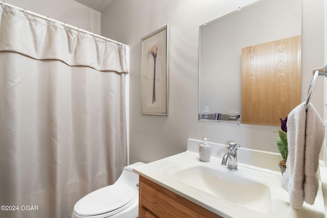 bathroom with curtained shower, vanity, and toilet