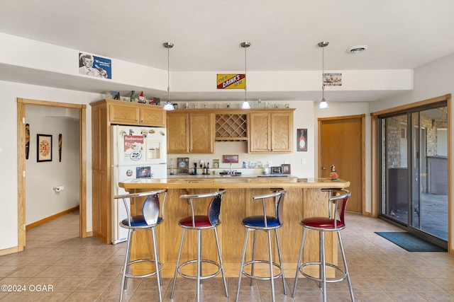 kitchen featuring a kitchen bar, light tile patterned floors, white refrigerator, a center island, and hanging light fixtures