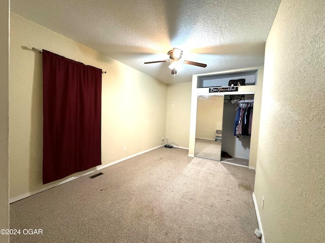 unfurnished bedroom featuring a textured ceiling, light colored carpet, a closet, and ceiling fan