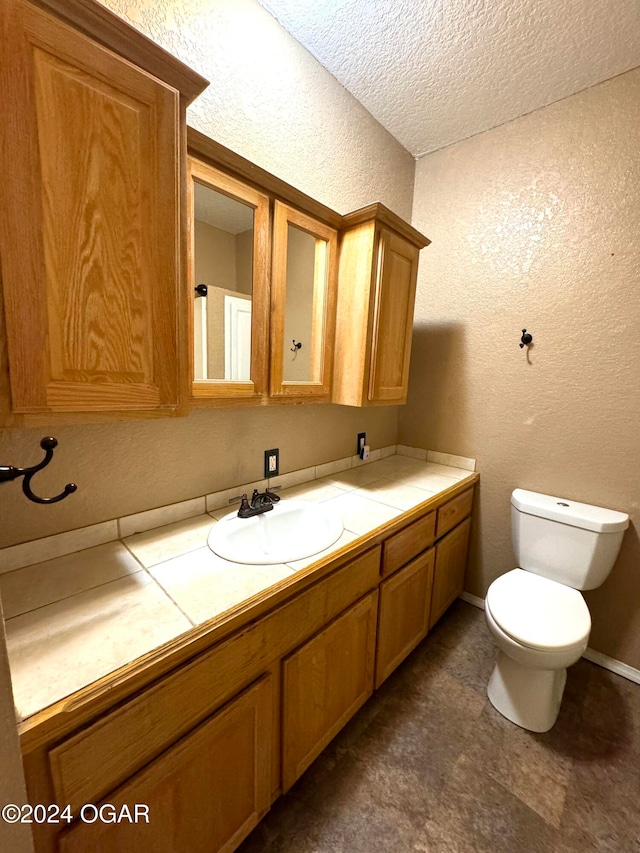 bathroom featuring a textured ceiling, vanity, and toilet