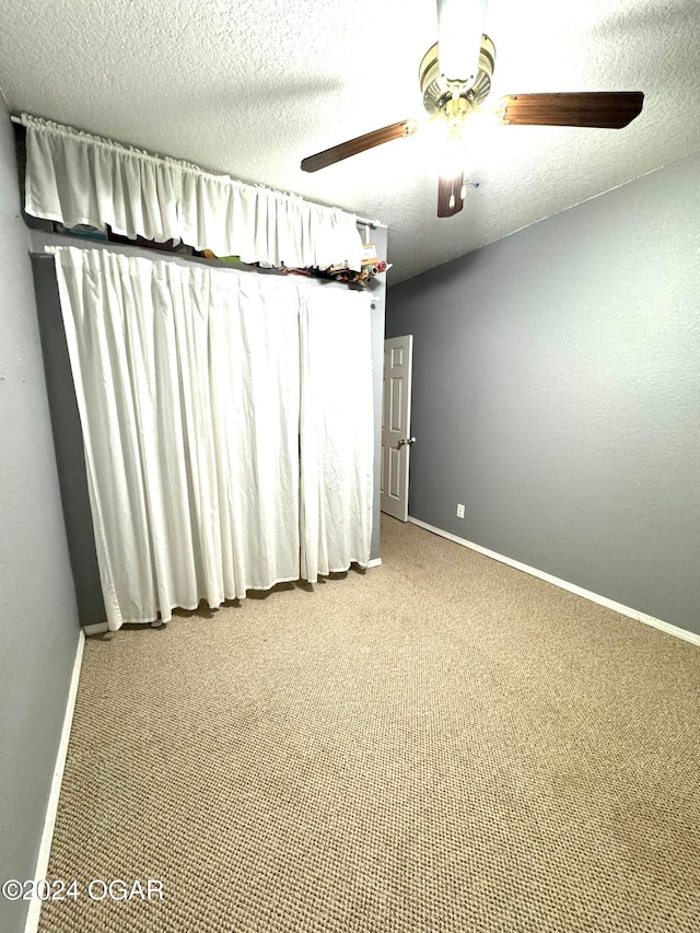 carpeted empty room with ceiling fan and a textured ceiling