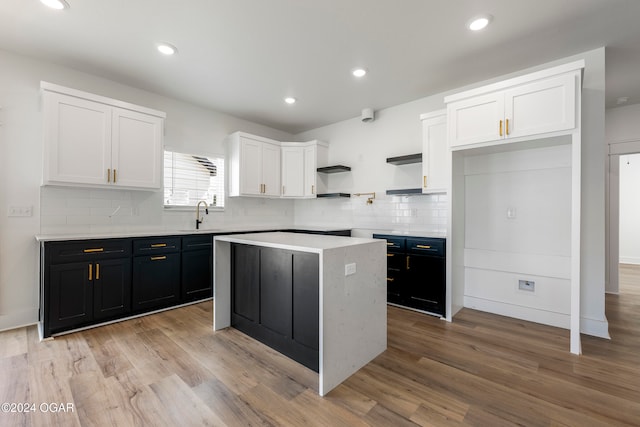 kitchen with white cabinets, decorative backsplash, a center island, and light hardwood / wood-style flooring