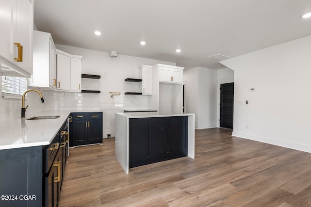 kitchen featuring white cabinetry, a center island, sink, tasteful backsplash, and light hardwood / wood-style floors