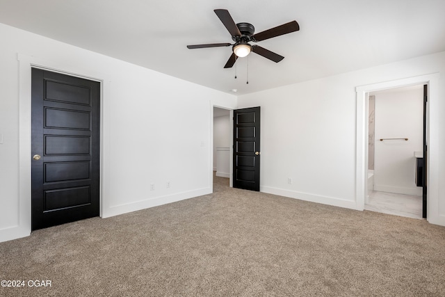 unfurnished bedroom with ceiling fan, light colored carpet, and connected bathroom