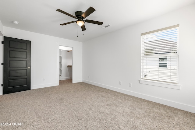 unfurnished bedroom with carpet, ceiling fan, a spacious closet, and a closet