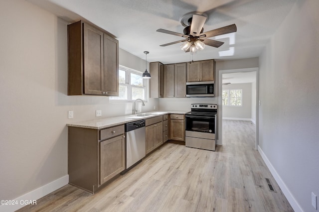 kitchen with hanging light fixtures, sink, stainless steel appliances, and a wealth of natural light