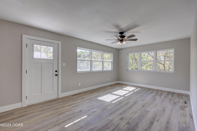 foyer entrance with a textured ceiling, light wood-type flooring, and ceiling fan