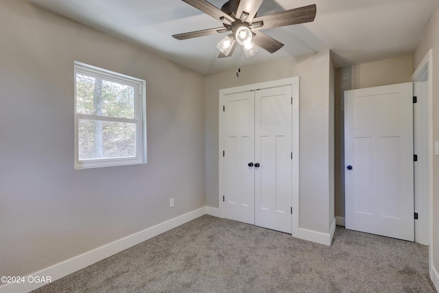 unfurnished bedroom featuring ceiling fan, a closet, and light colored carpet