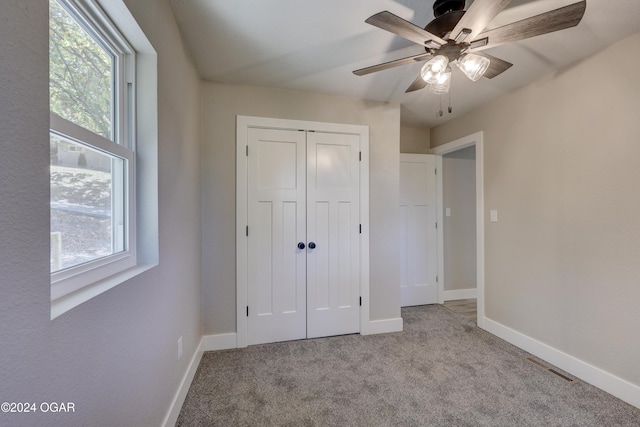 unfurnished bedroom featuring ceiling fan, light colored carpet, and a closet