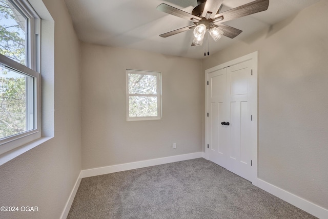 unfurnished bedroom with ceiling fan, a closet, light colored carpet, and multiple windows