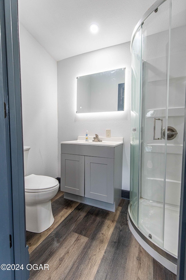 bathroom with vanity, hardwood / wood-style flooring, toilet, and a shower with shower door