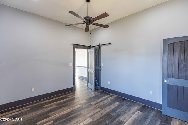 unfurnished room featuring a barn door, vaulted ceiling, ceiling fan, and dark wood-type flooring