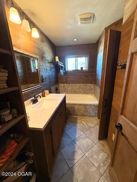 bathroom featuring tile patterned flooring, vanity, and a relaxing tiled tub