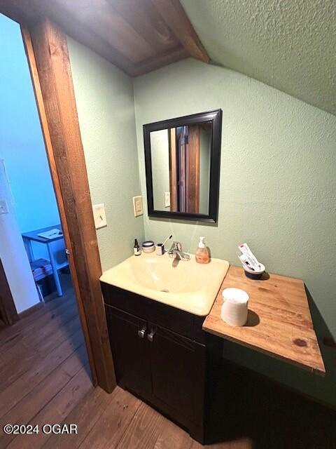 bathroom with vaulted ceiling with beams, vanity, and hardwood / wood-style flooring