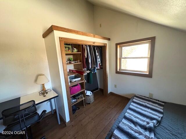 bedroom with a textured ceiling, lofted ceiling, and dark hardwood / wood-style floors