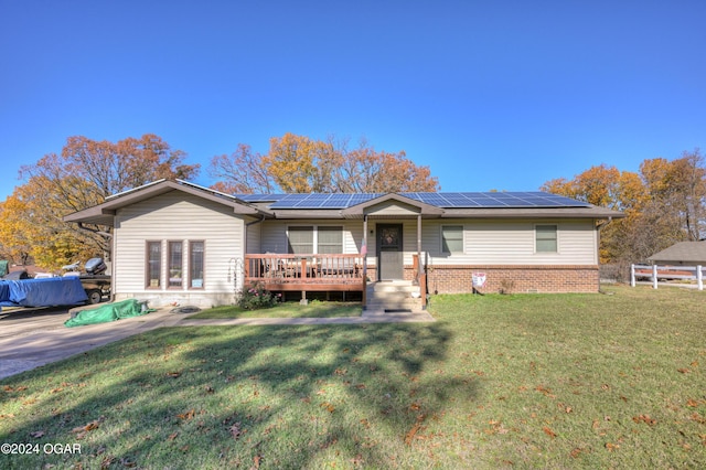 single story home featuring solar panels, a wooden deck, and a front lawn