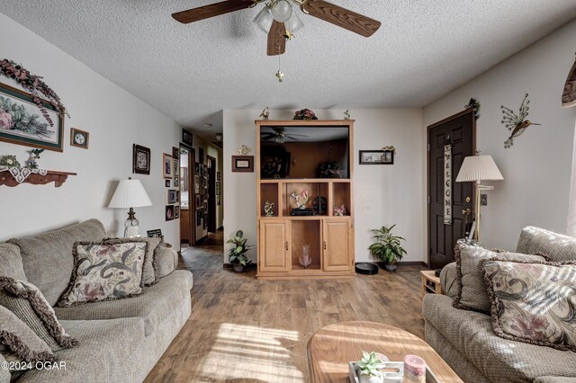 living room featuring ceiling fan, wood-type flooring, and a textured ceiling