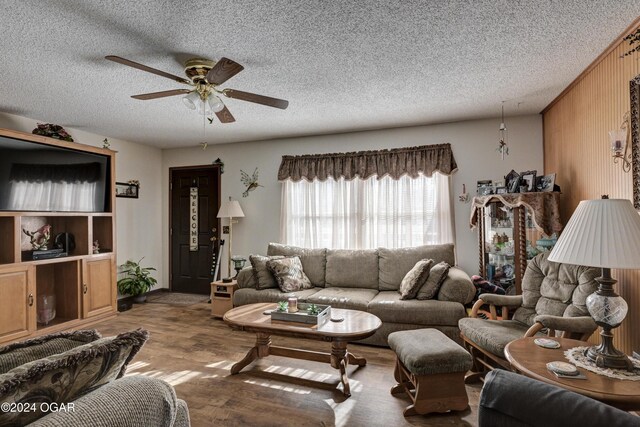 living room featuring ceiling fan, hardwood / wood-style floors, and a textured ceiling