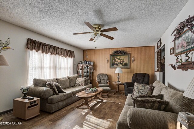 living room featuring wood walls, dark hardwood / wood-style flooring, ceiling fan, and a textured ceiling