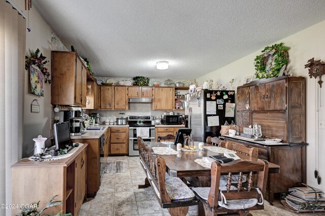 kitchen with backsplash, sink, a textured ceiling, and appliances with stainless steel finishes