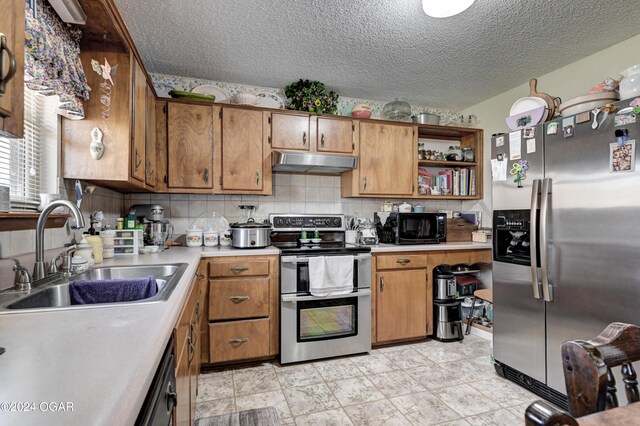 kitchen with decorative backsplash, sink, stainless steel appliances, and a textured ceiling