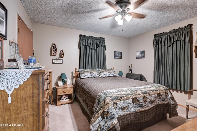 bedroom featuring ceiling fan, light colored carpet, and a textured ceiling